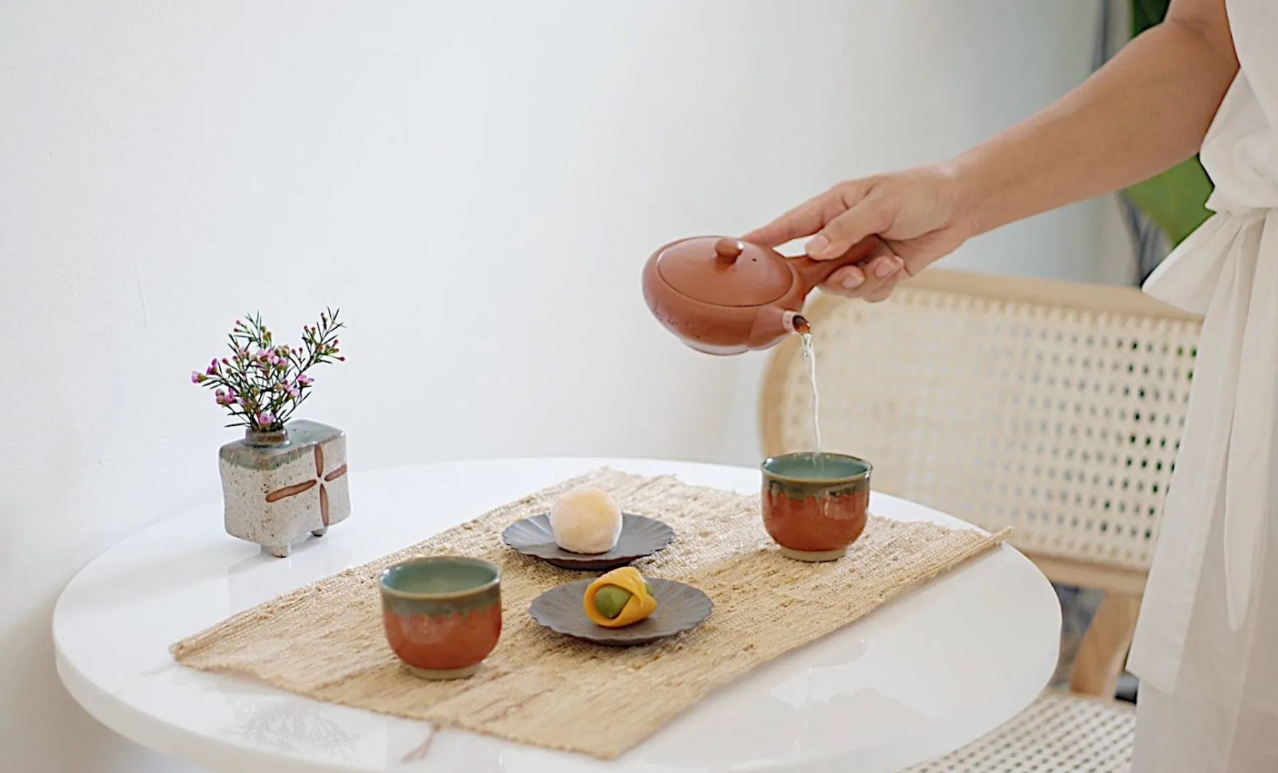 Japanese tea being poured with two wagashi sweets